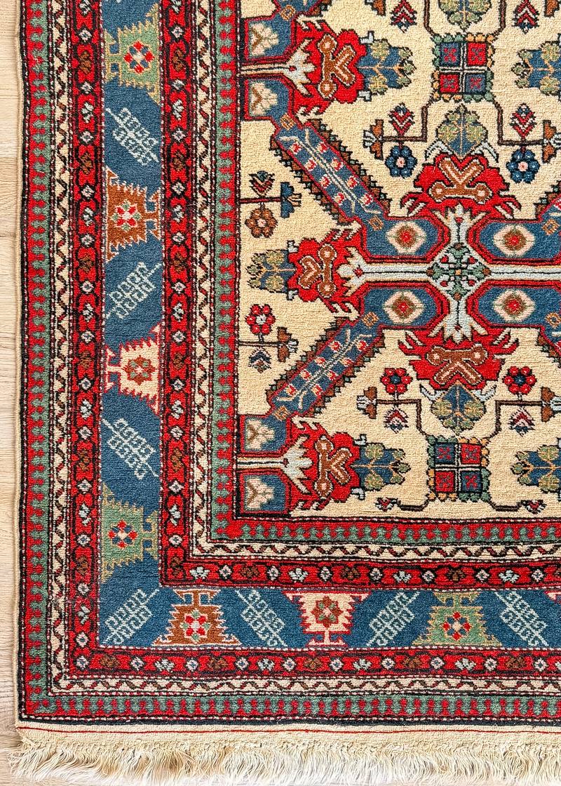 Corner of Leyla, a vintage Kuba-design rug with an ivory field and a blue border